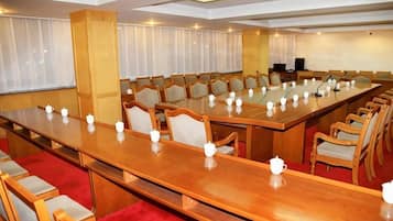 A conference room with a long table, chairs, and a projector screen.