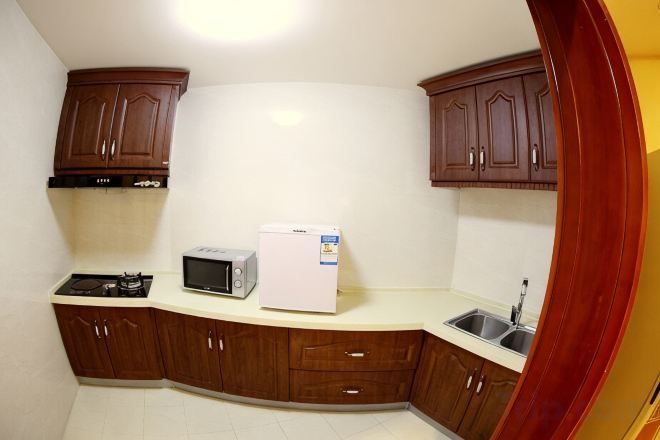 A kitchen with wooden cabinets, a microwave, and a refrigerator.