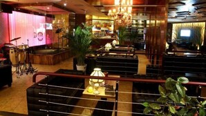 Een hotel lobby met een podium, een zithoek en een bar.