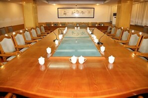 Una sala de conferències amb una taula llarga, cadires, micròfons i teieres.
