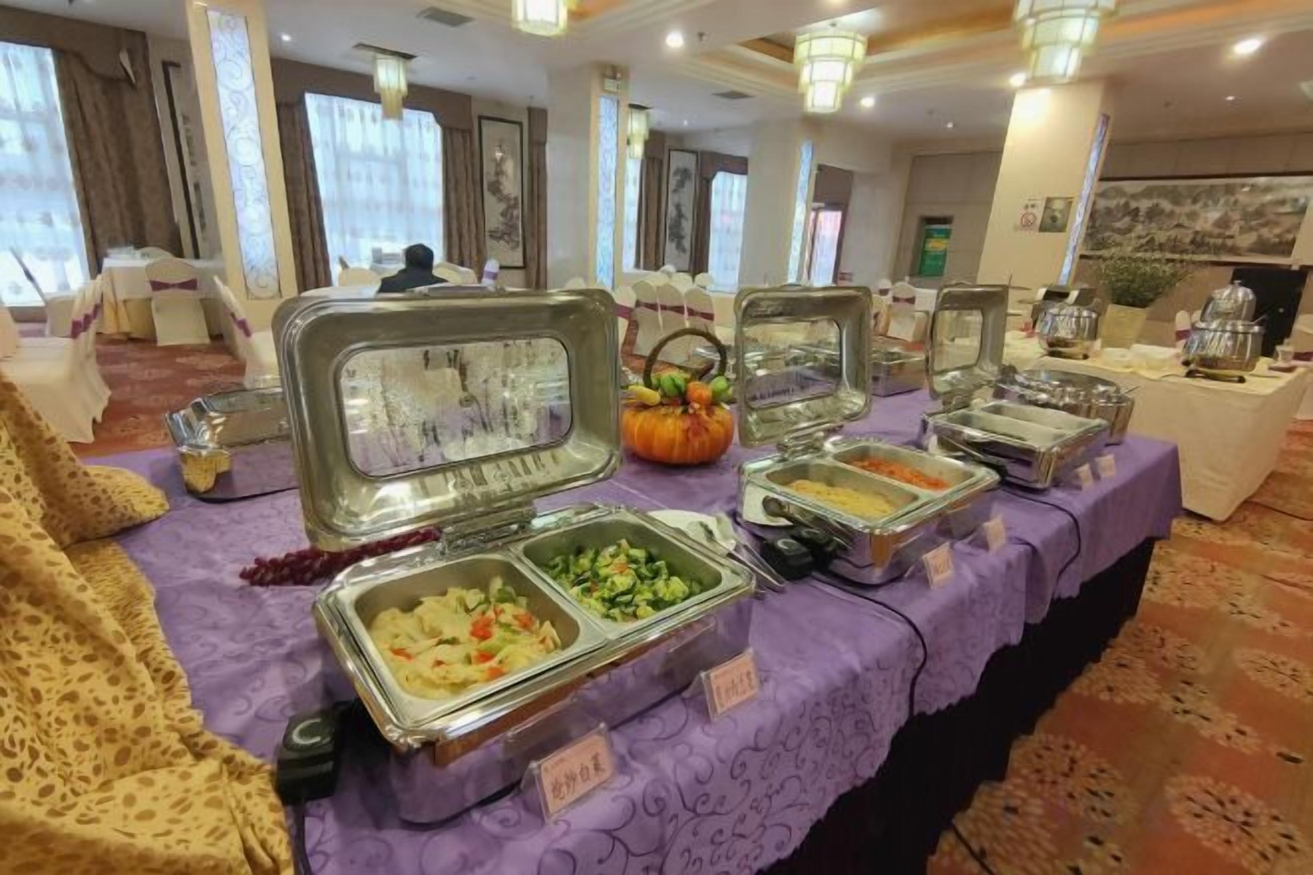 A buffet table with various food containers, a pumpkin decoration, and a sign indicating 'Asian Cuisine.'