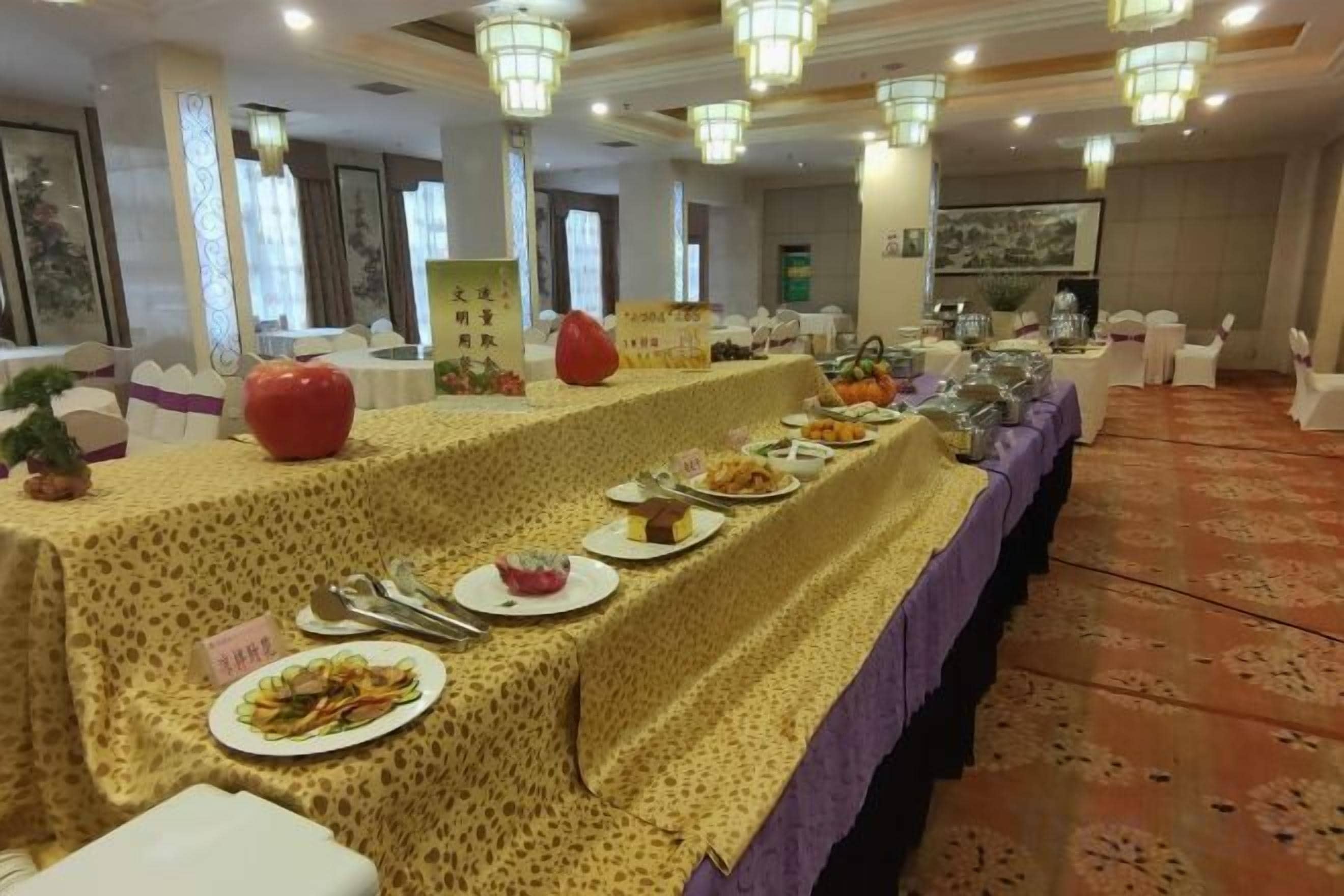 Una mesa de banquete dispuesta con diversos platos, un mantel estampado y un suelo alfombrado.