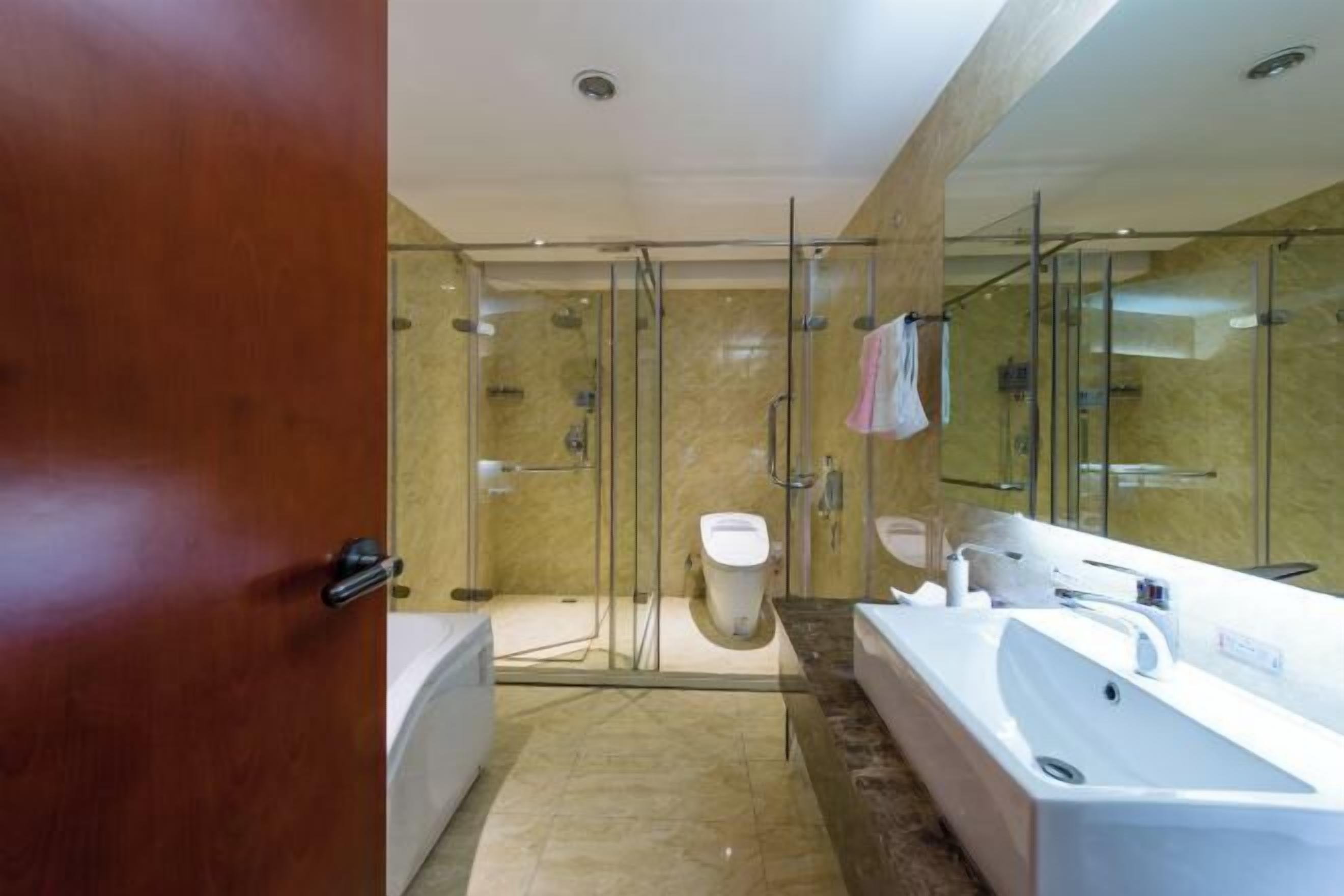 Un baño moderno con ducha de vidrio, una bañera amplia y un inodoro separado.