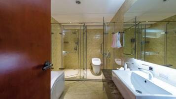 Un baño moderno con ducha de vidrio, una bañera amplia y un inodoro separado.