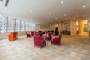 A spacious lobby with a patterned carpet, multiple seating areas, and a reception desk. - Tianma Hotel (Wuwei)