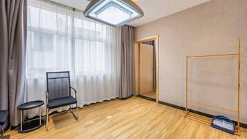 Quarto com aquecedor no teto, uma cadeira, uma mesinha, guarda-roupa e espelho.