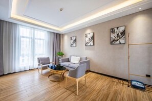 A modern living room with a sofa, two armchairs, a coffee table, and abstract wall art. - Kaiqi Hotel (Hanzhong)