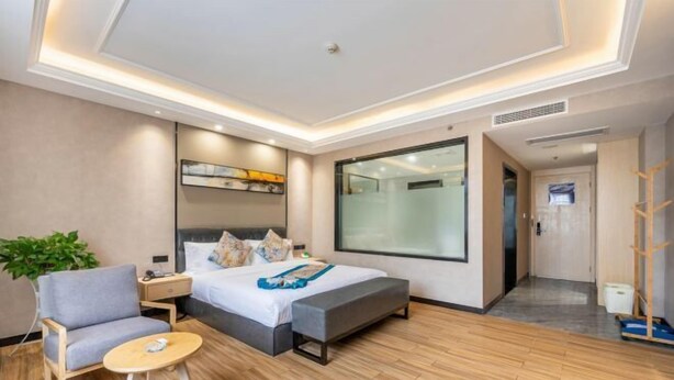 A modern hotel room with a bed, bedside table, chair, and a small round table.