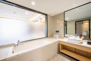 Ein modernes Badezimmer mit einer großen Badewanne, einem Waschbecken und einem Spiegel.