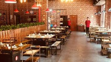 A restaurant with brick walls, multiple tables, and hanging red pendant lights.