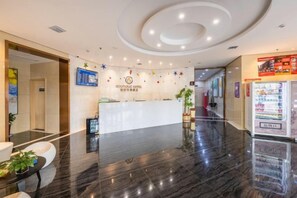 A hotel reception area with a marble floor, a reception desk, and a vending machine.