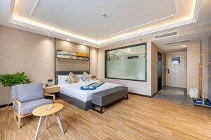 Habitación de hotel moderna con cama, mesita de noche, silla y una pequeña mesa.