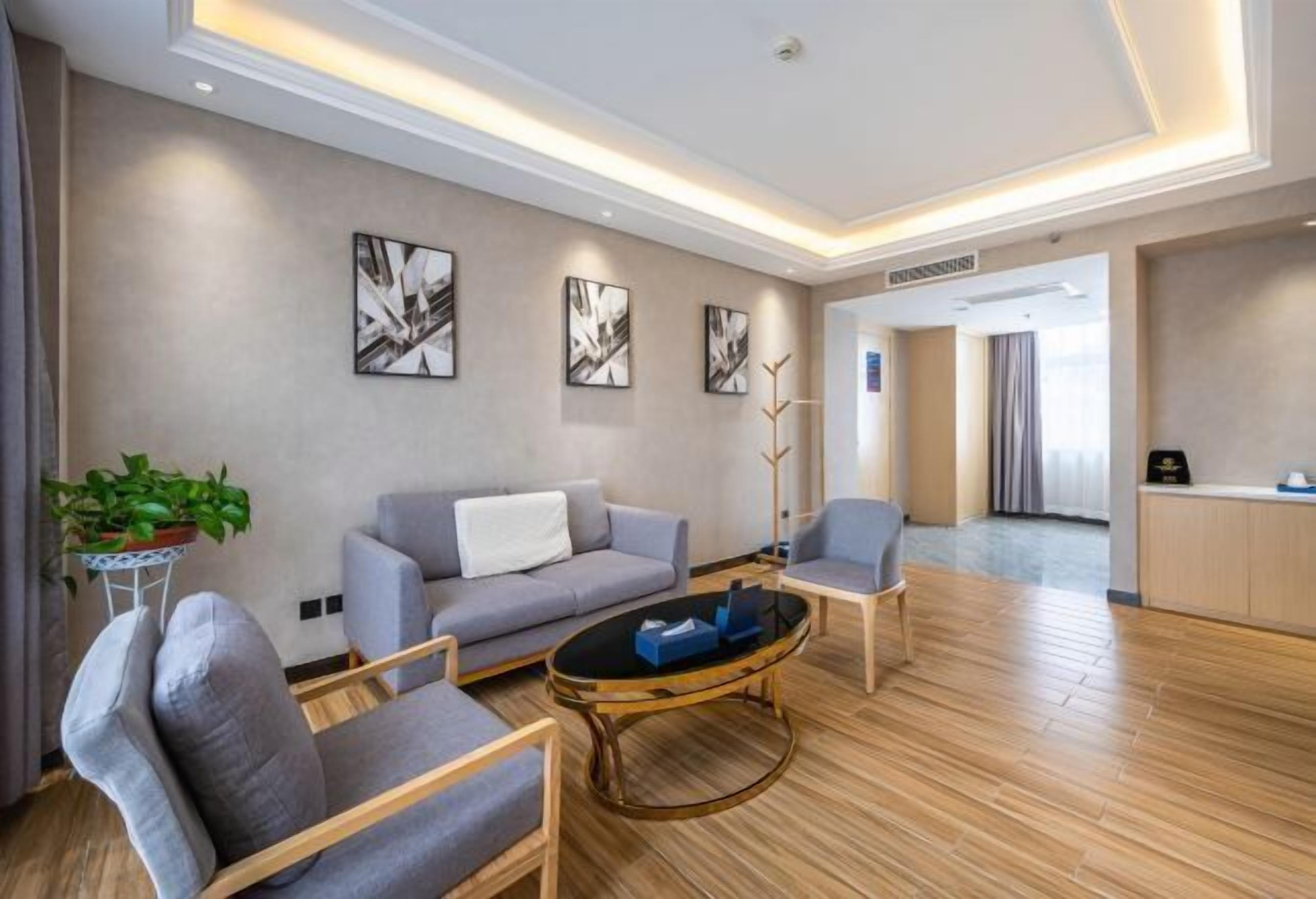 A modern living room with a sofa, armchairs, a coffee table, and abstract wall art.