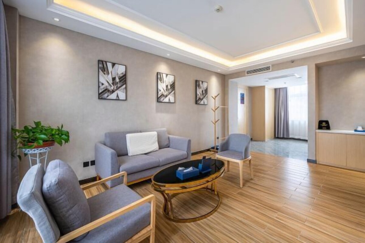 A modern living room with a sofa, armchairs, a coffee table, and abstract wall art.