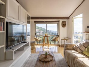 A spacious living room with a balcony, a television, a sofa, and a dining area with chairs. - Casa Alfonso by Interhome (Pietrabruna)