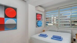 Um quarto moderno com uma cama, uma janela com persianas e arte abstrata na parede.