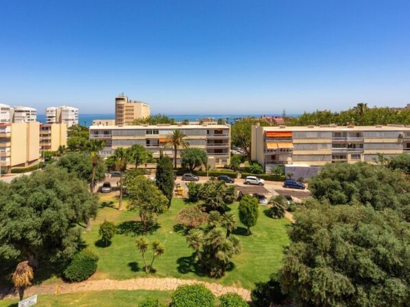 Zona residencial con edificios de varios pisos, un patio con césped y vista al mar.