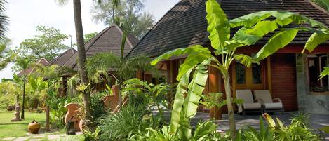 Un resort con varias construcciones tipo bungalow, exuberantes jardines tropicales y un césped bien cuidado.