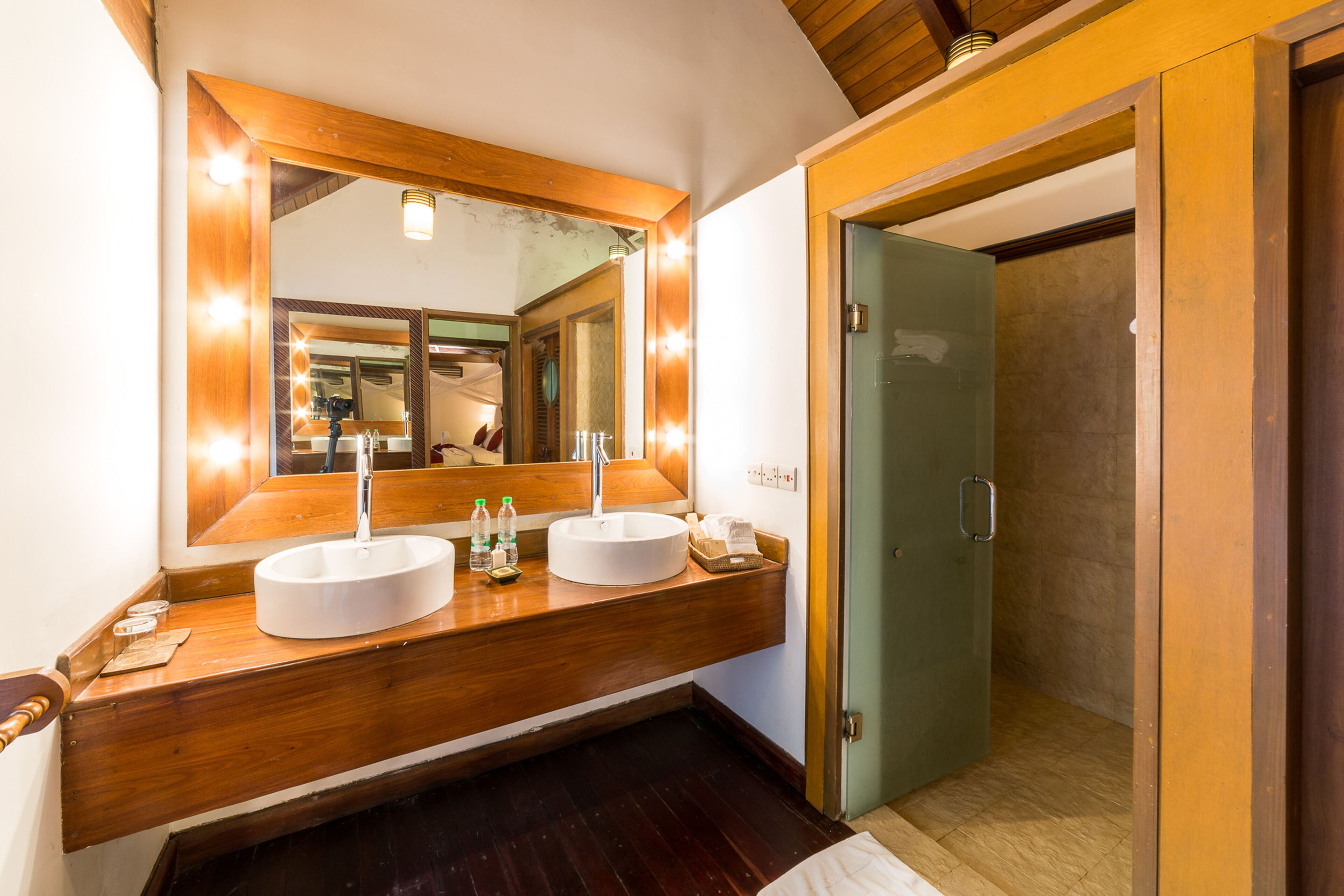 A bathroom with two sinks, a large mirror, and a glass shower door.