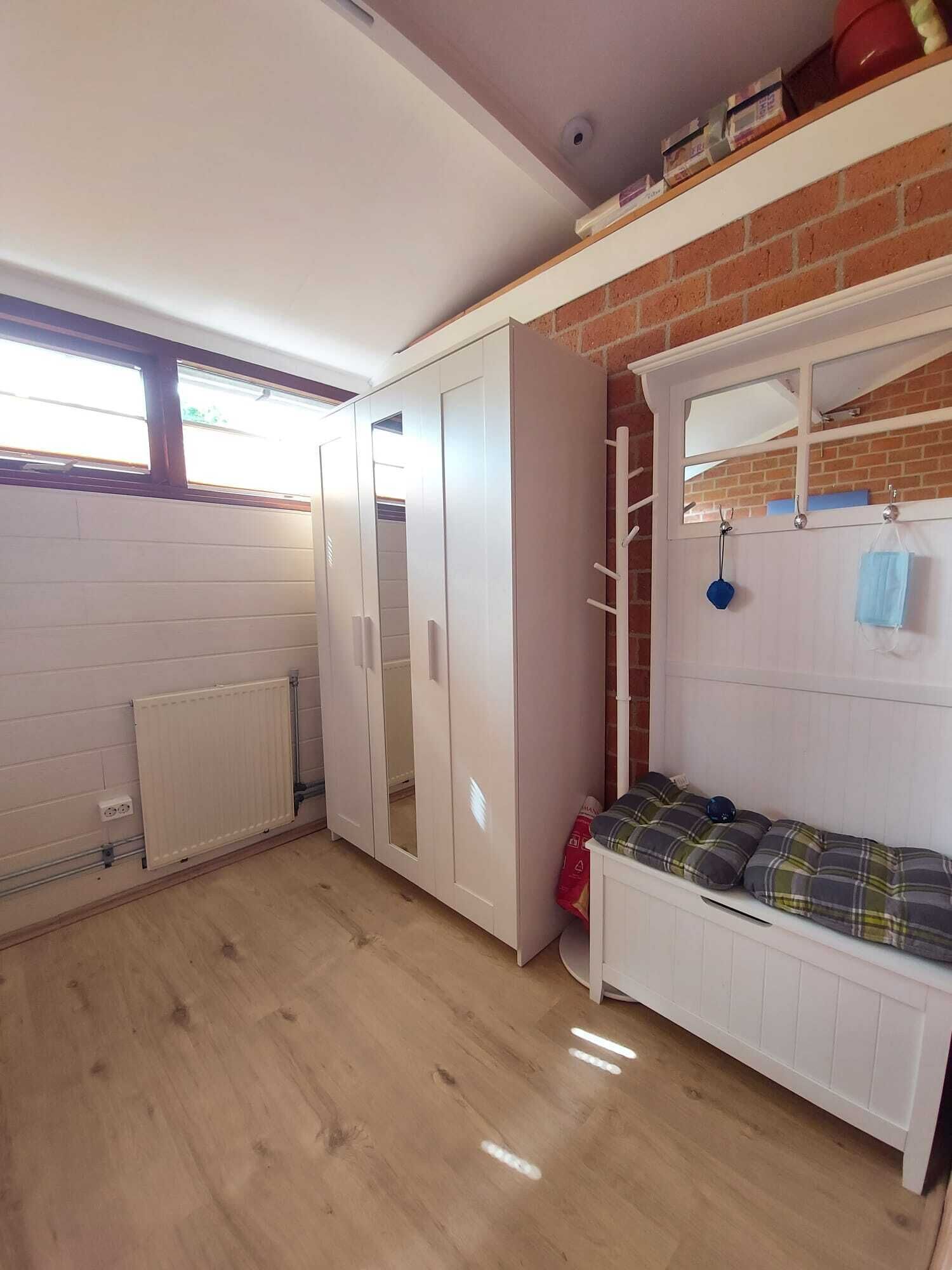 A room with a loft bed, a radiator, a wardrobe, and a window.