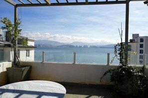 A balcony with a view of a body of water and distant mountains. - Hersy Vista · Hesi 270° Panoramic Erhai-Cangshan View Boutique Stay (Dali City)