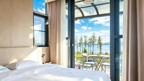 A hotel room with a bed, a window, and a view of the sea. - Hersy Vista · Hesi 270° Panoramic Erhai-Cangshan View Boutique Stay (Dali City)