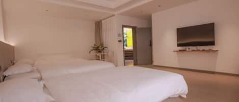 A modern hotel room with two large beds, a flat-screen TV mounted on the wall, and a small side table with a plant.