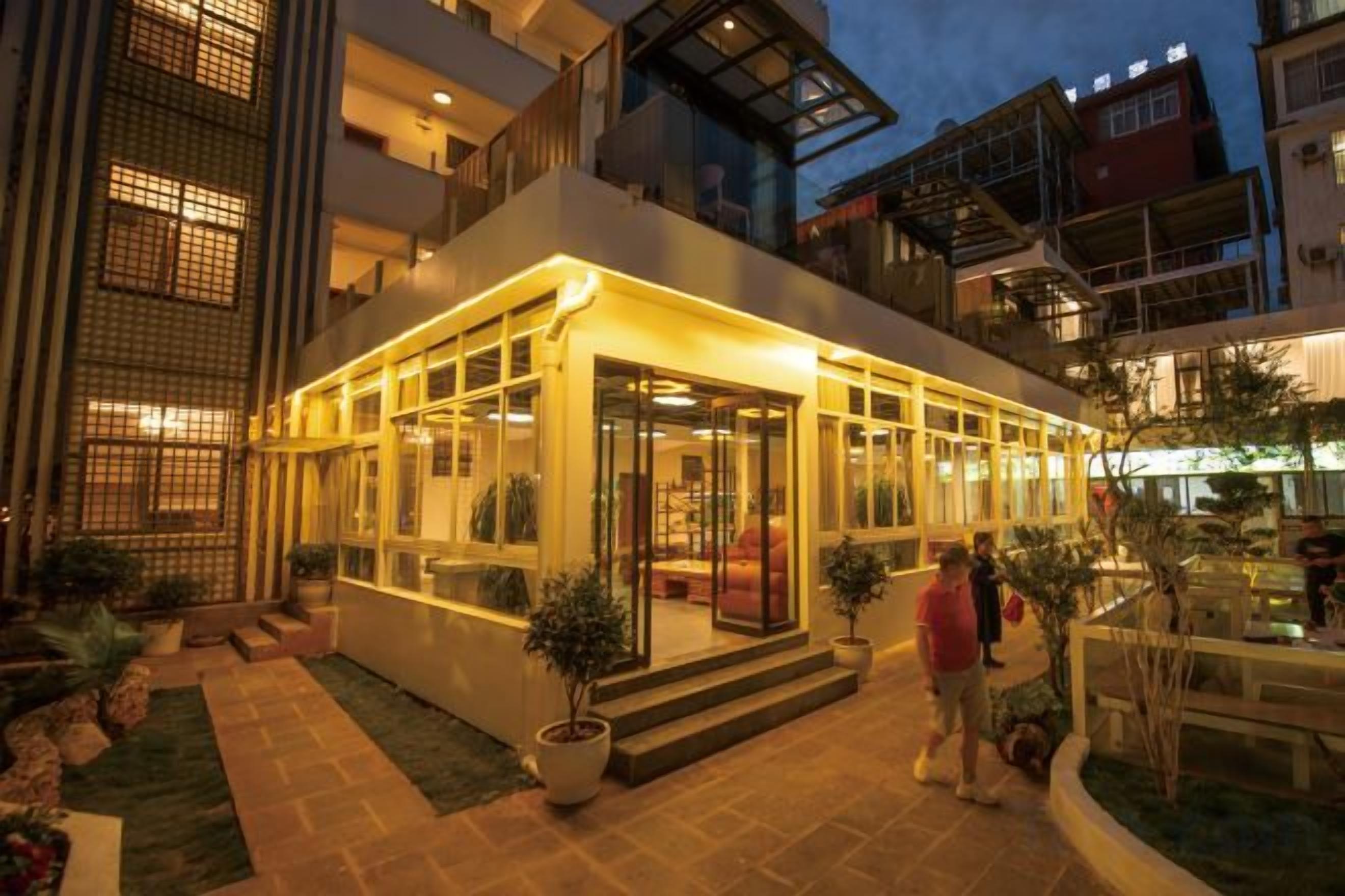 Un edificio moderno con fachada de vidrio, zona de estar al aire libre y una entrada bien iluminada.