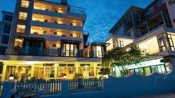 A multi-story hotel with balconies, a covered outdoor area, and a reflective pool.