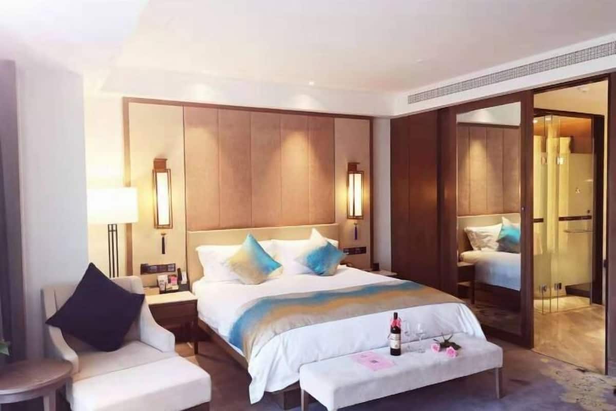 Ein Hotelzimmer mit einem großen Bett, Nachttischen, einem Sessel und einer Bank.