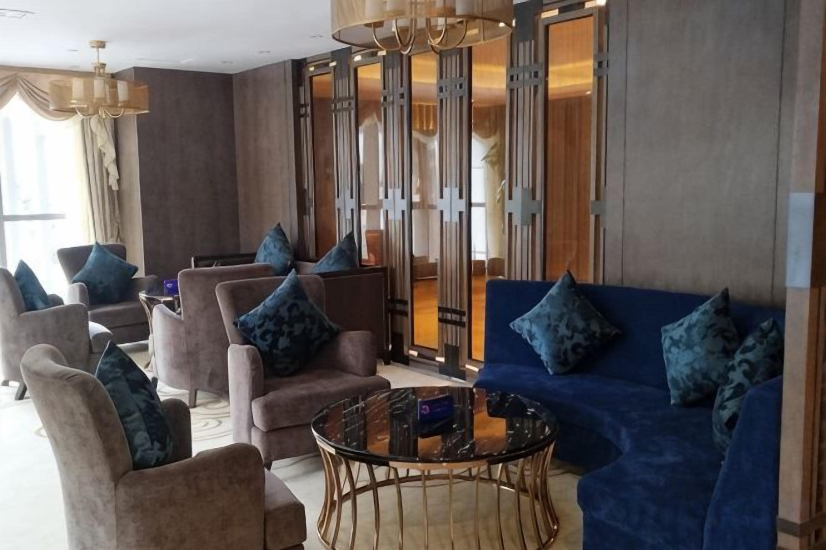 A hotel lobby with sofas, armchairs, a coffee table, and a large window.
