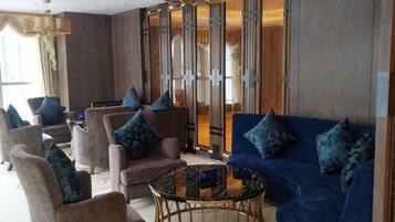 A hotel lobby with sofas, armchairs, a coffee table, and a large window.