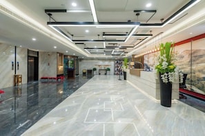 A hotel lobby with a marble floor, a reception desk, and a large window with a view. - Chengtou Gangwan Hotel (Zunyi)