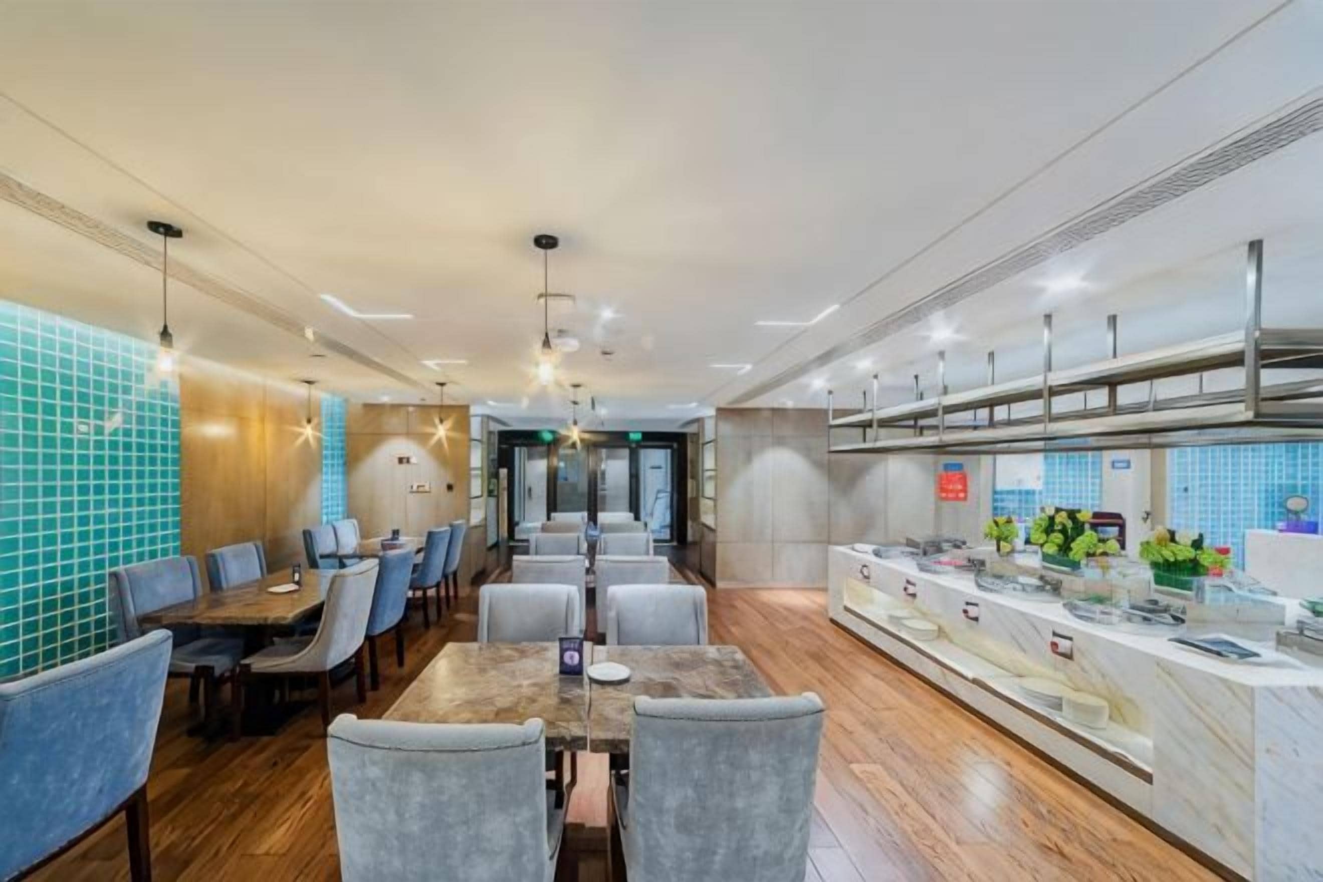 A modern restaurant with a long counter, multiple tables, and a kitchen area.