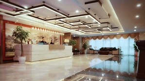 A hotel reception area with a modern design, a reception desk, and a large potted plant. - Chengtou Gangwan Hotel (Zunyi)