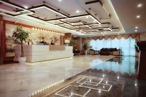 Een hotel receptie met een modern design, een receptiebalie en een grote potplant.