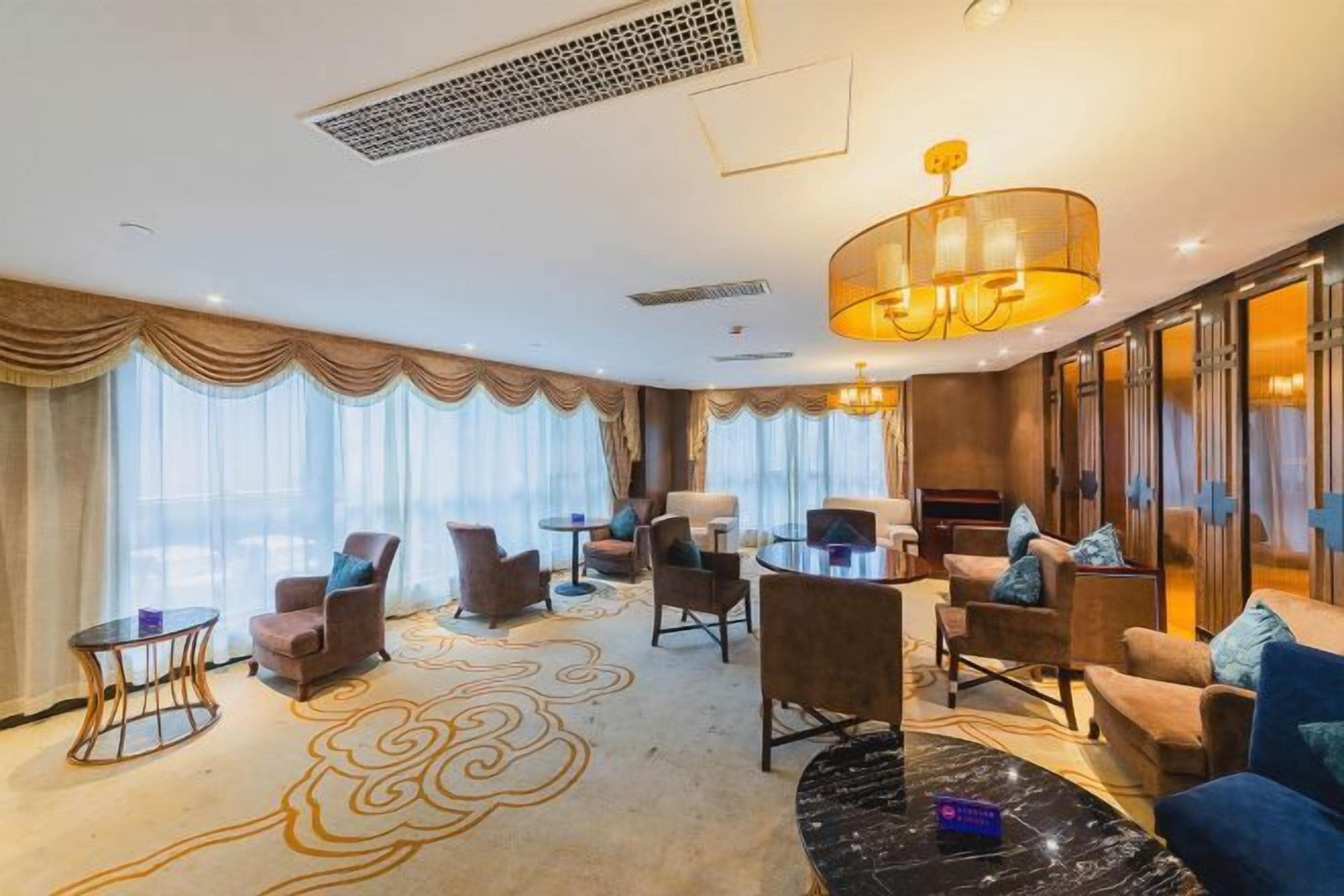 A hotel lobby with a seating area, a coffee table, and a large chandelier.