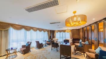 A hotel lobby with a seating area, a coffee table, and a large chandelier.