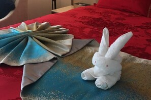 A bed with a red and gold patterned bedspread, a folded blue and gold cloth, and a white plush toy resembling a rabbit. - Chengtou Gangwan Hotel (Zunyi)