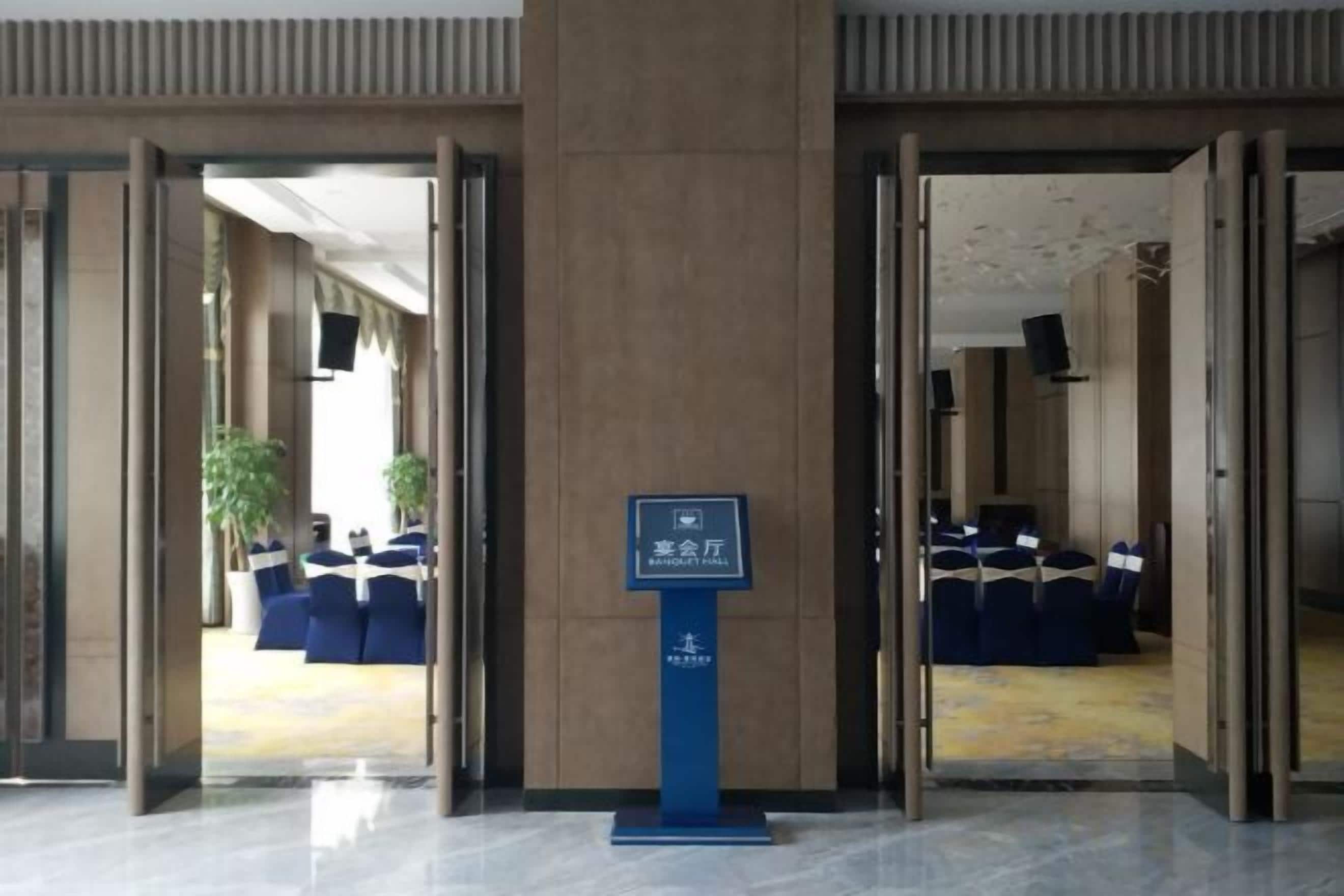 A hotel lobby with a reception desk, seating area, and a sign indicating a business center.