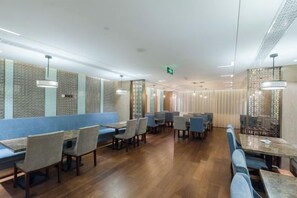 A modern restaurant with wooden flooring, blue seating, and pendant lighting. - Chengtou Gangwan Hotel (Zunyi)