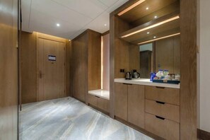 A modern bathroom with wooden cabinets, a marble floor, and a vanity with a mirror. - Chengtou Gangwan Hotel (Zunyi)