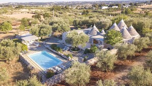 A resort with a swimming pool, outdoor seating, and conical-roofed structures. - TD Trulli Locobello Stylish Cozy Trulli w Pool (Martina Franca)