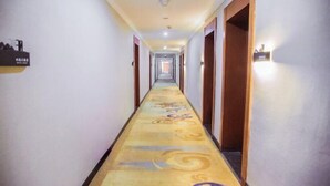 A long, narrow hotel corridor with a patterned carpet, wooden doors, and a light fixture on the wall. - Beiliu Grand Hotel (Guijiang Pearl Pedestrian Street) (Beiliu)