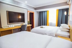Habitación de hotel con dos camas, un escritorio, un televisor de pantalla plana y una ventana con cortinas.