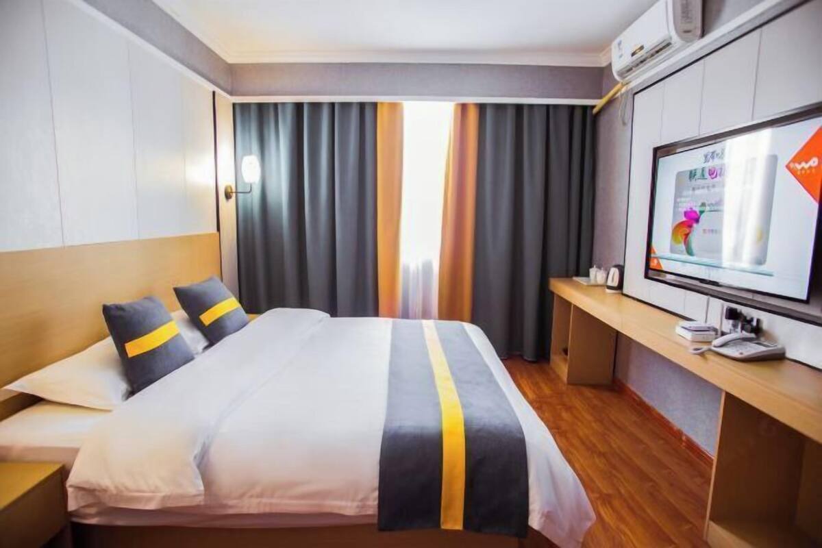 A hotel room with a bed, a desk, and a television.