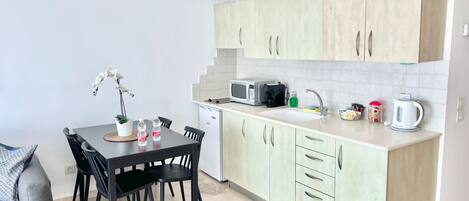 Cocina compacta con área de comedor, que incluye microondas, lavabo y armarios.