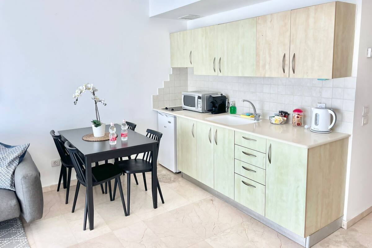 A compact kitchen with a dining area, featuring a microwave, sink, and cabinets.