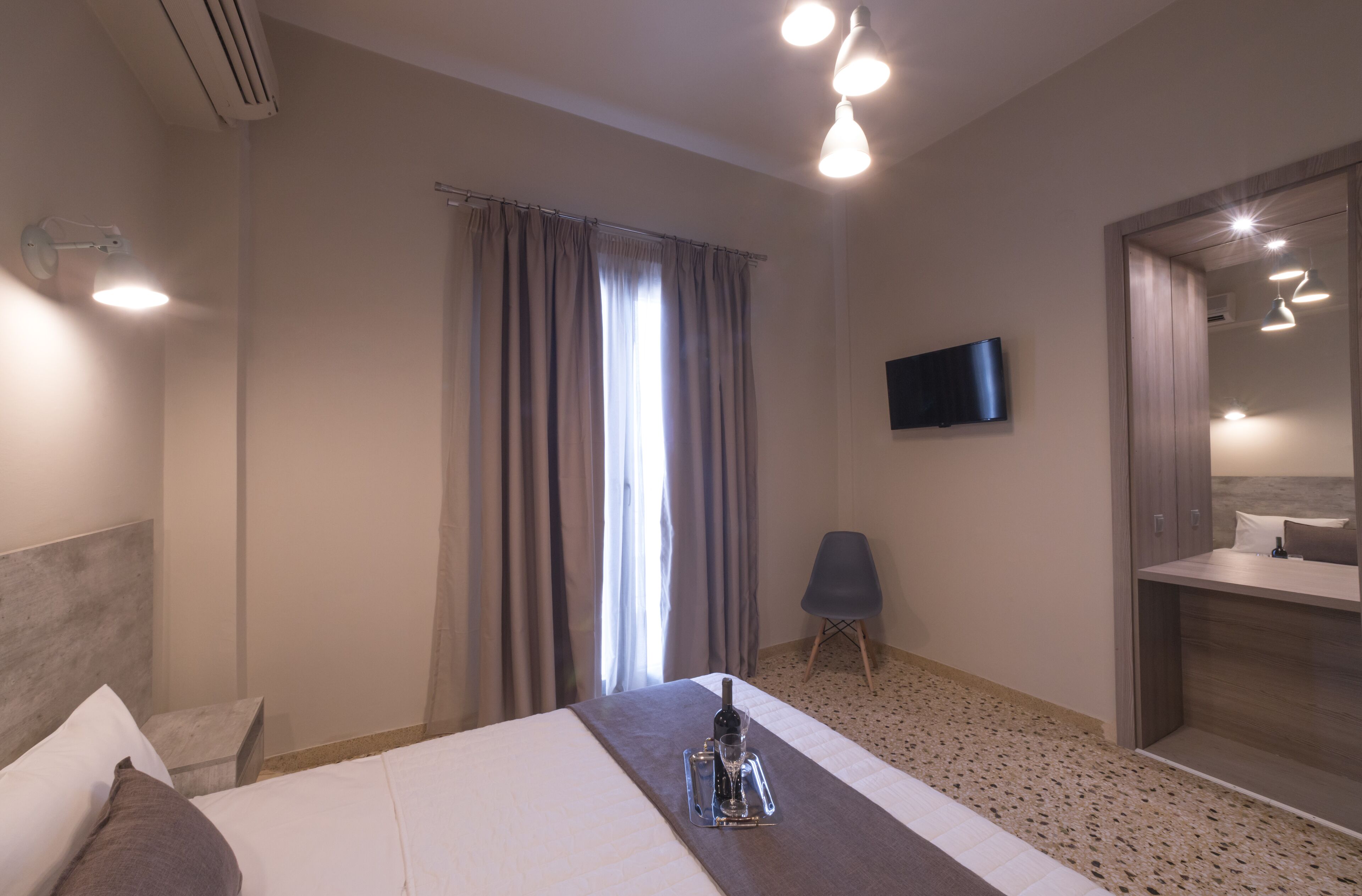 A hotel room with a bed, a TV, a chair, and a bathroom.