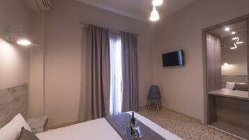 A hotel room with a bed, a TV, a chair, and a bathroom.